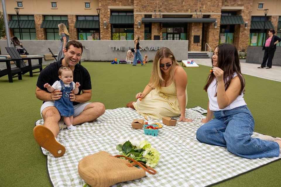 Shoppers sitting on a picnic blanket at The Backyard in The Shops at Highland Village | Image courtesy of The Shops at Highland Village