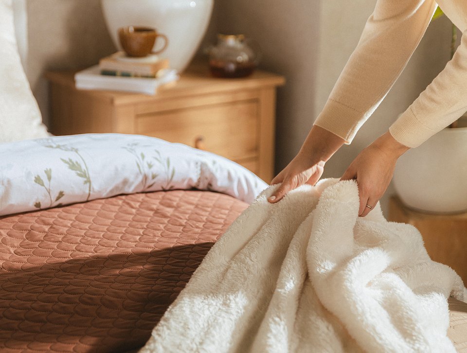 Miks rozmaitych faktur tekstyliów, przemyślanie dobrany, to gotowy przepis na ciekawą aranżację sypialni.