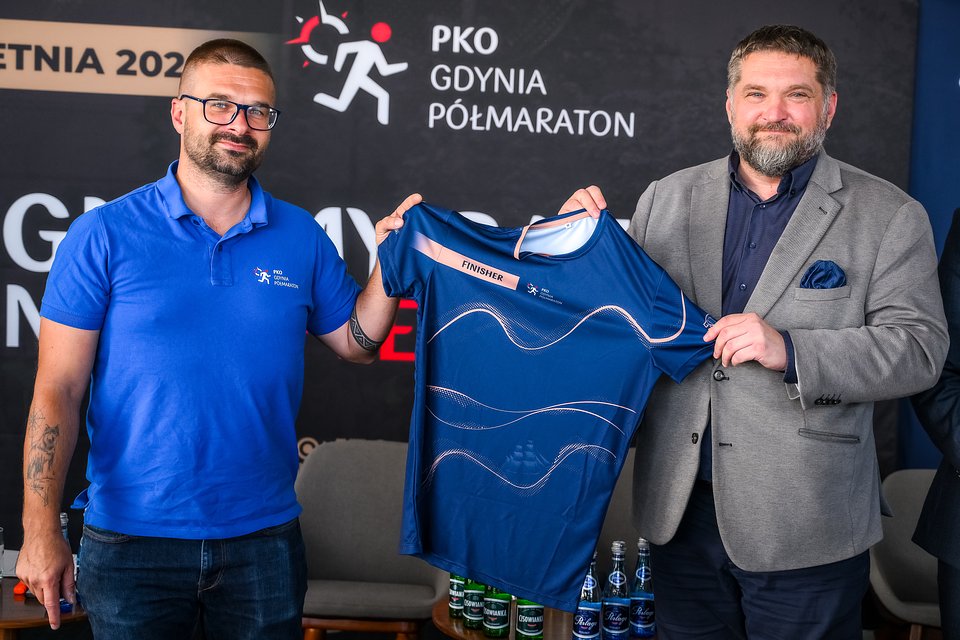 Michał Drelich (z lewej) i Tadeusz Szemiot (z prawej) - przewodniczący Rada Miasta Gdyni, prezentują oficjalną koszulkę finiszer'a PKO Gdynia Półmaratonu 2026 / Fot. Przemek Świderski / Sport Evolution
