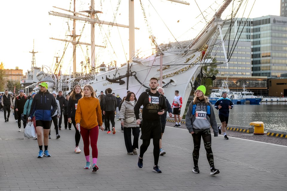 Biegacze zmierzający na start PKO Gdynia Półmaratonu 2025. W tle Dar Pomorza i ORP Błyskawica / Fot.: Przemek Świderski / Sport Evolution