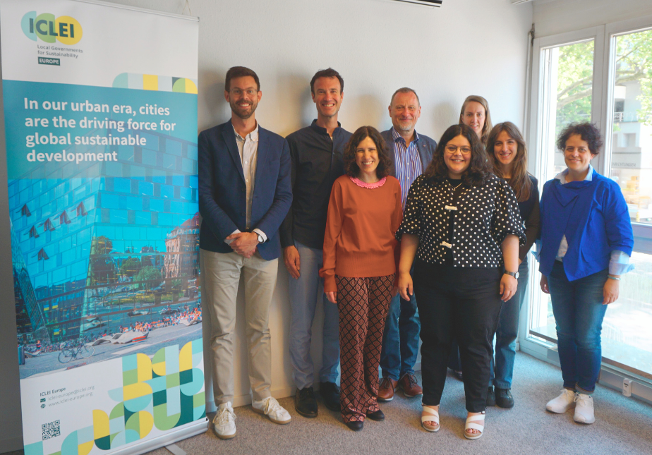 Gruppenfoto (von links nach rechts) von Mitarbeitenden von ICLEI Europe mit der Europaabgeordneten Vivien Costanzo im ICLEI Europe-Büro in Freiburg.
Hintere Reihe: Andreas Piller, Experte für nachhaltige Mobilität bei ICLEI Europe; Ruud Schuthof, stellvertretender Regionaldirektor bei ICLEI Europe; Wolfgang Teubner, Regionaldirektor bei ICLEI Europe; Helen Franzen, Leiterin für Strategische Kommunikation, Mitgliedschaft und Interessenvertretung bei ICLEI Europe.
Vordere Reihe: Dr. Cristina Garzillo, Leiterin für gebaute Umwelt, Kultur und Kulturerbe; Vivien Costanzo, Mitglied des Europäischen Parlaments; Benedetta Buccolini, Expertin bei ICLEI Europe; Ana Dragutescu, Leiterin für nachhaltige Mobilität bei ICLEI Europe.